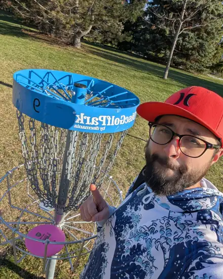 Coach Tetsuro Ide next to a disc golf basket